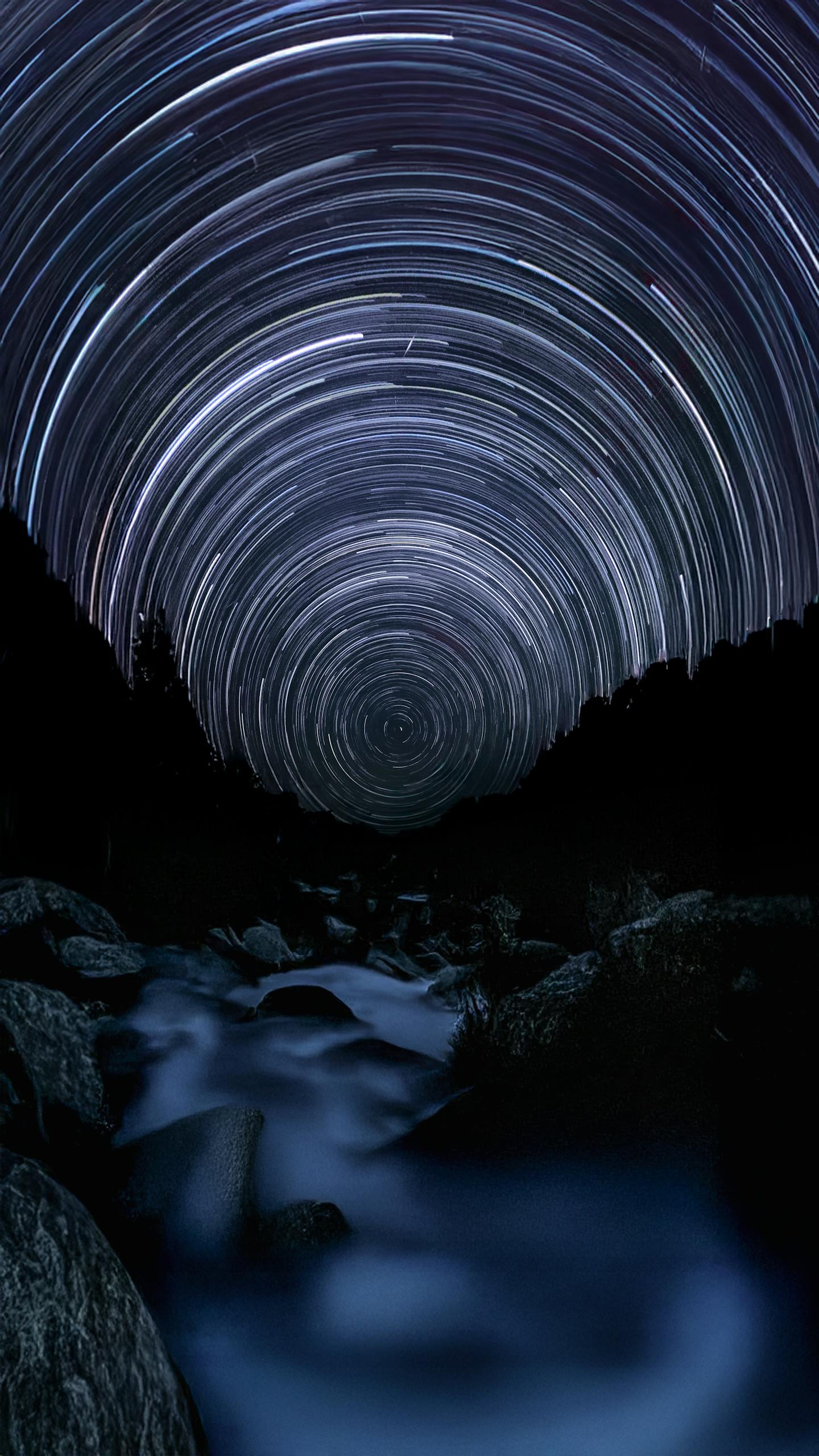 Long exposure captures stunning star trails above a tranquil river in the forest. Perfect for astronomy and nature enthusiasts.